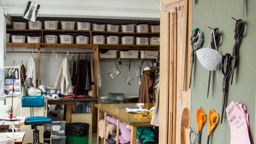 A room with sewing machines, rolls of material, a table and other sewing equipment.