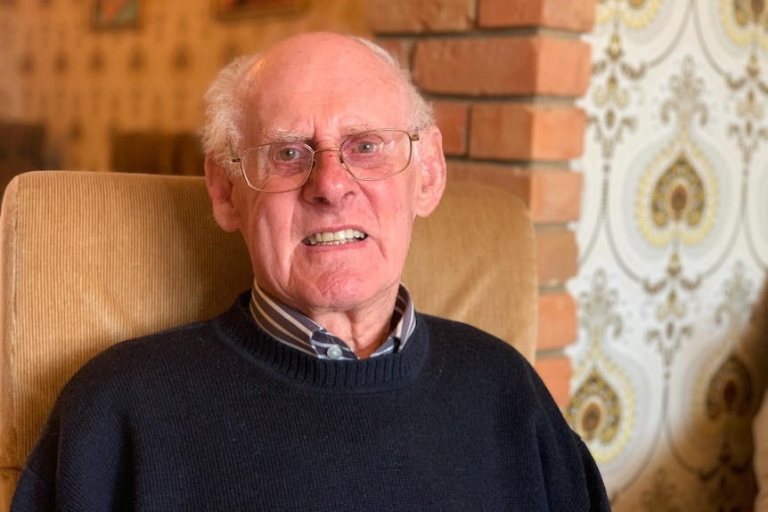 An elderly man smiles at the camera