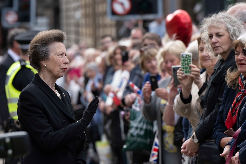 Princess Anne speaks with a crowd of people standing behind a barricade. 