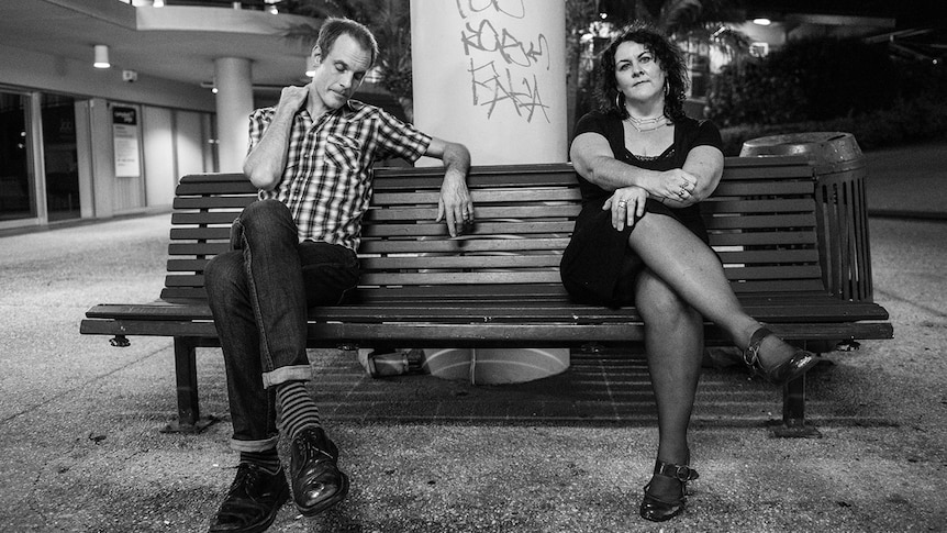 Black and white photo of Tim Steward and Kellie Lloyd of Screamfeeder sitting on a bench in an outdoor mall