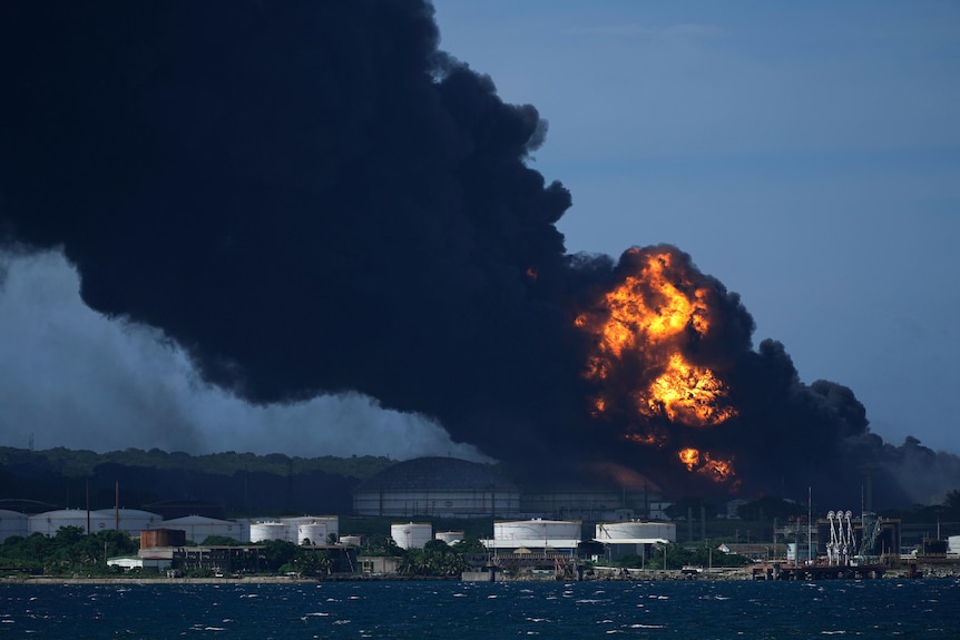 Flames tower above an industrial building, with thigh black smoke billowing from the blaze