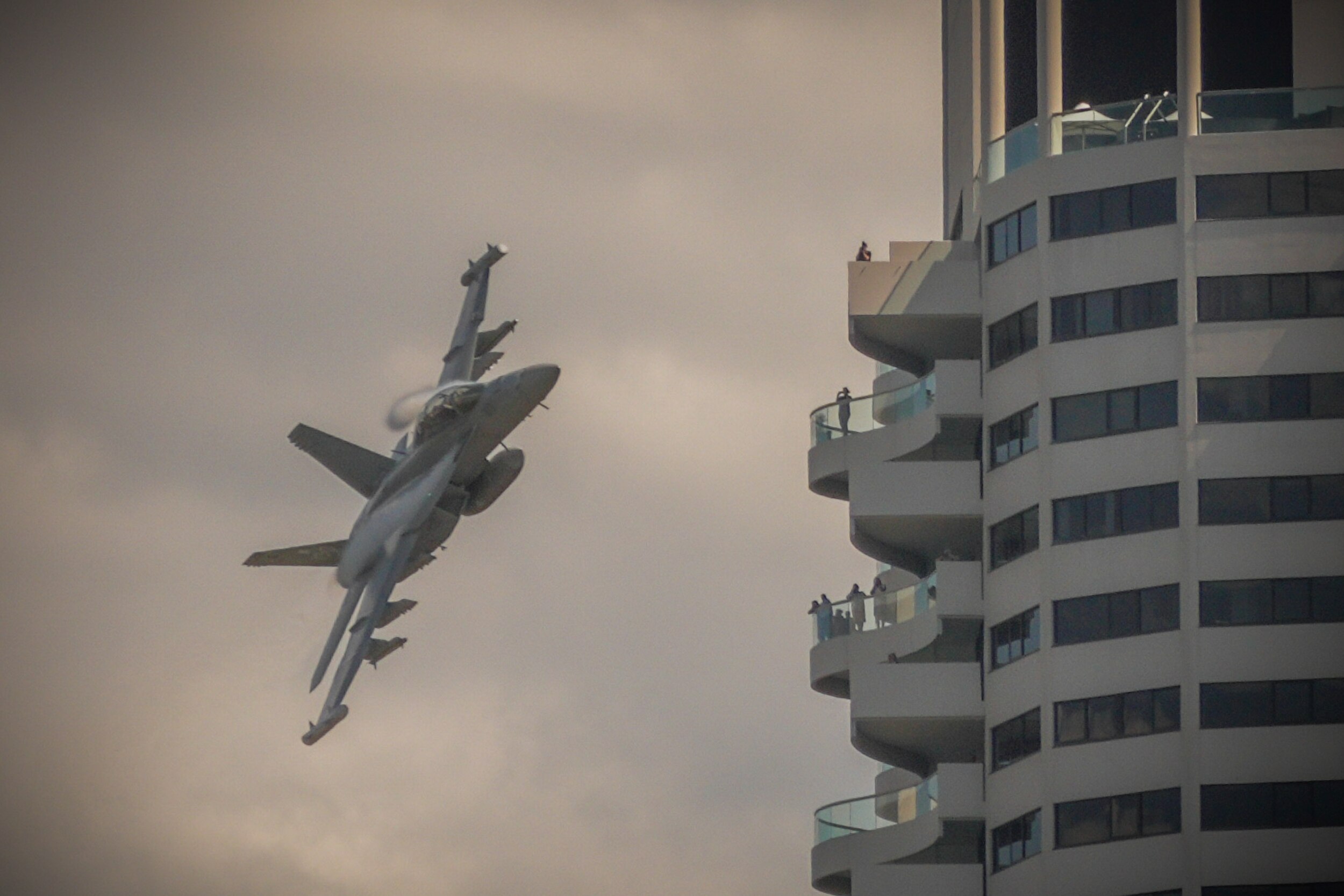 A Growler plane flying close by a building. 