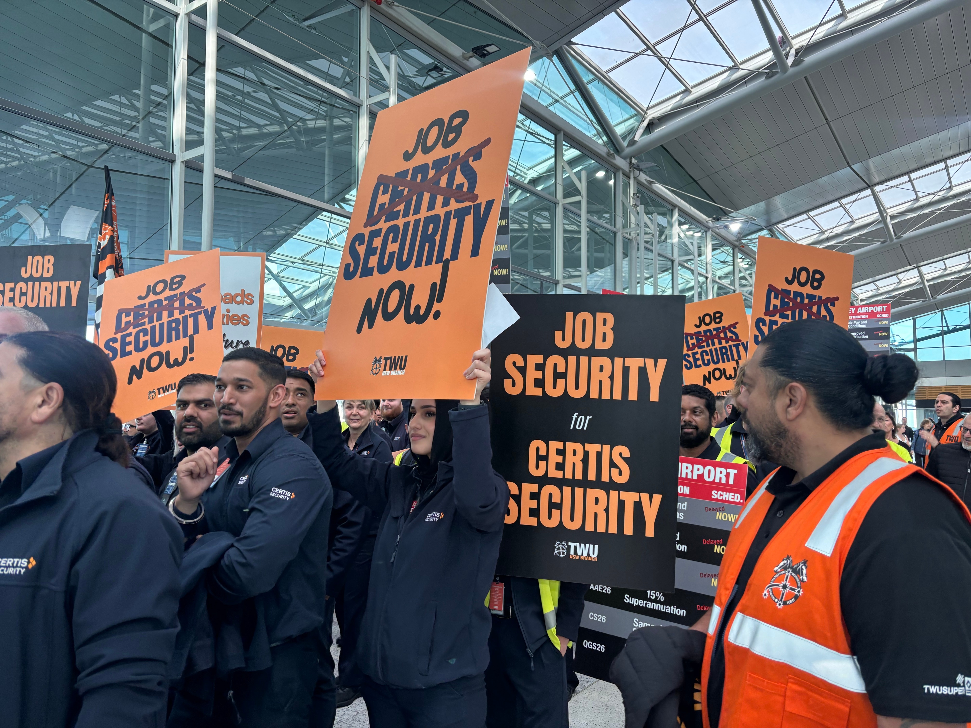 A group of people carry signs calling for better job security.