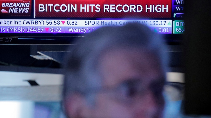 a person's face infront of a screen showing bitcoin record