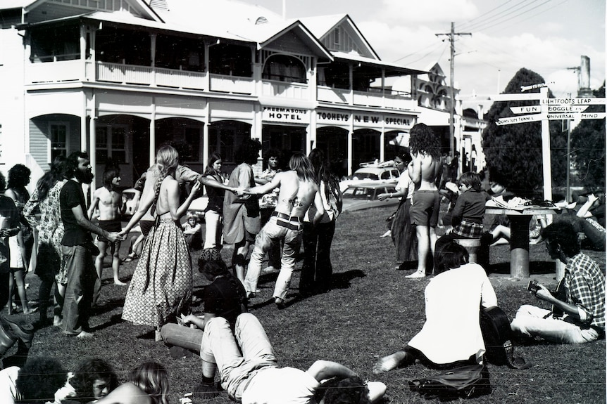 A black and white photo of young people dancing in a street in a town