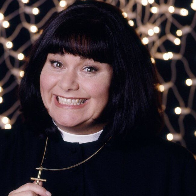 Dawn French dressed as a vicar all in black, with her trademark short dark bob haircut and wearing a crucifix.