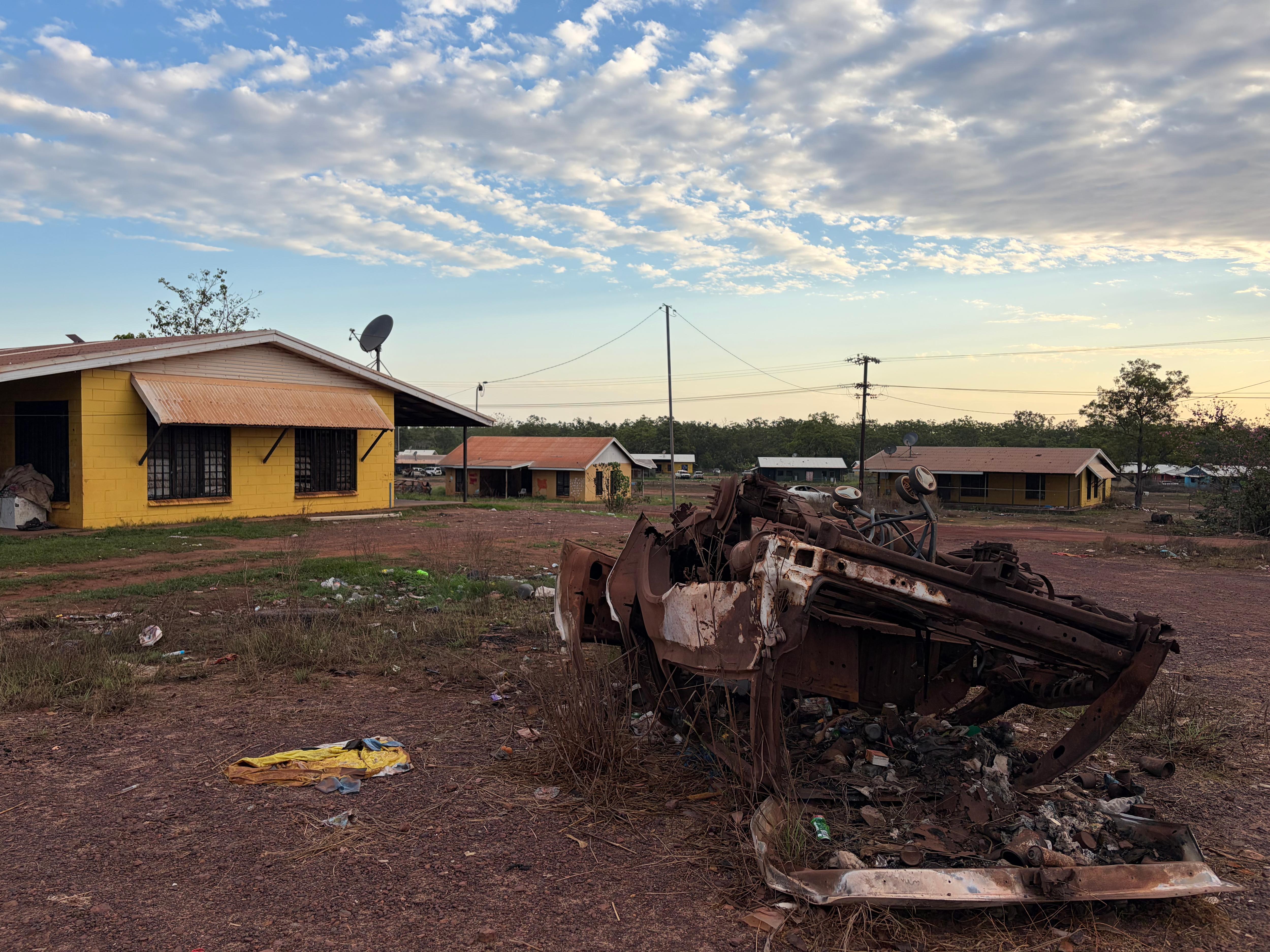 Burnt out car sits in front of house in Wadeye.