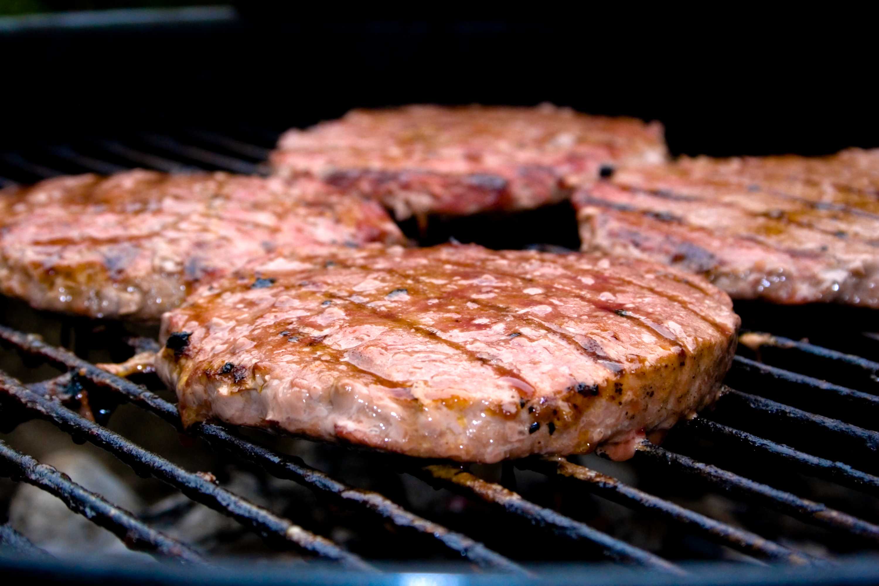 Four pieces of steak on a barbecue.