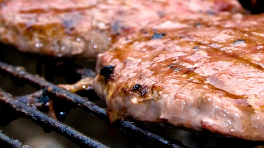 Four pieces of steak on a barbecue.