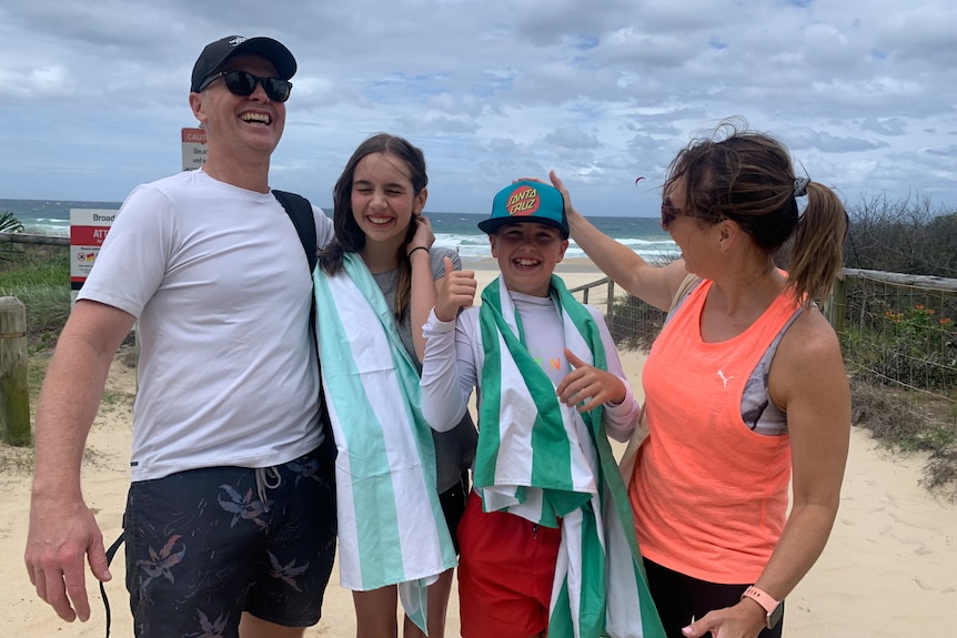 A man, two children and a woman laughing while at the beach