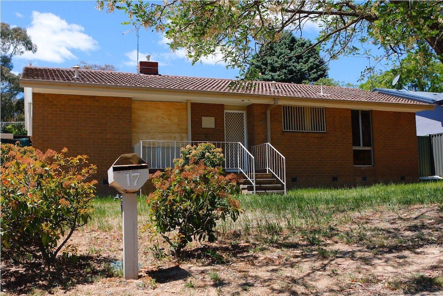 The Waramanga house where a man was tasered by police shortly before his death, with a front window boarded-up.