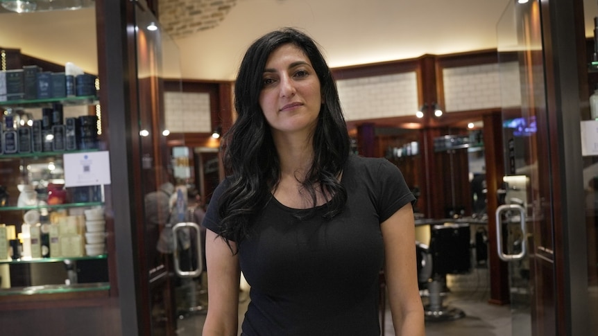 A woman wearing a black dress, standing in a hairdressing salon