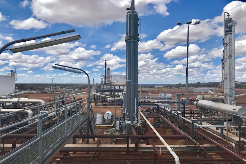 Industrial looking processing plant in front of red dirt and blue sky.