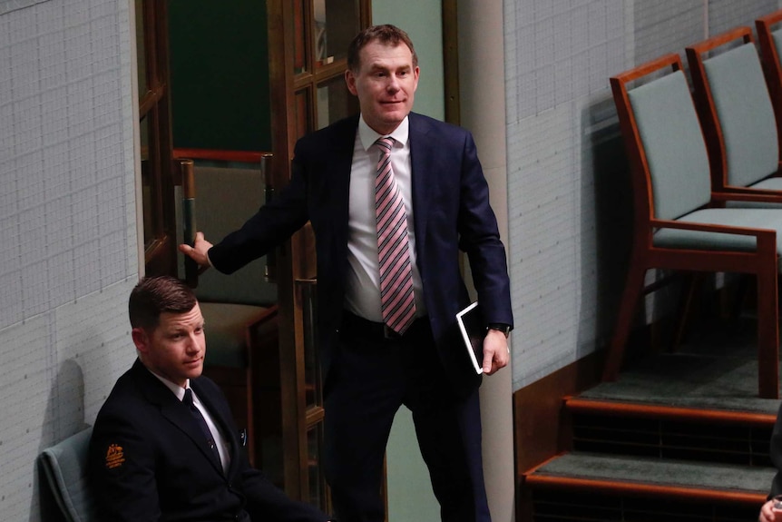 Nick Champion leaves the House of Representatives chamber, wearing a navy blue suit and a pink striped tie.