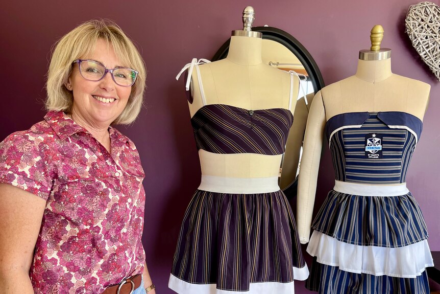 A woman stands next to two dressmakers dolls displaying altered school uniforms
