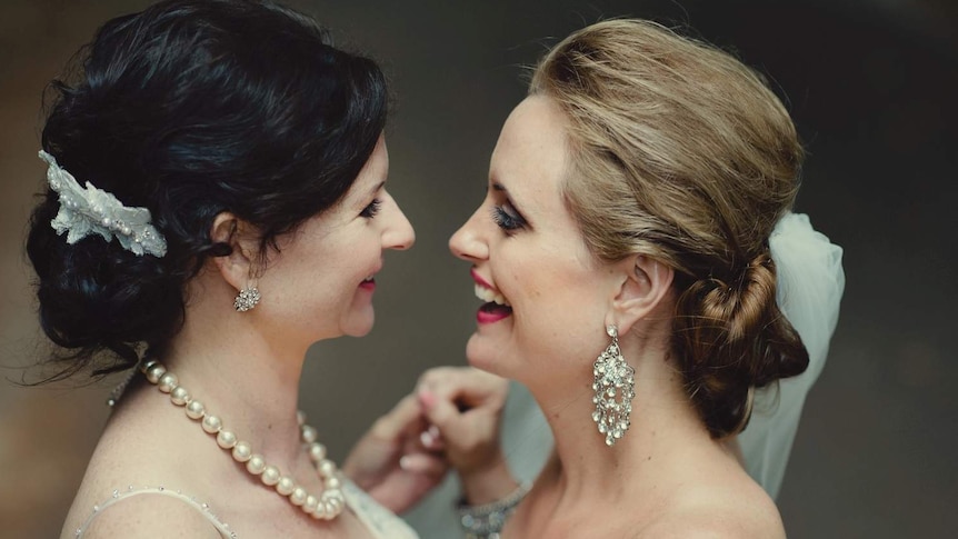Leonie and Kate hold hand smiling towards each other at their commitment ceremony in 2011.