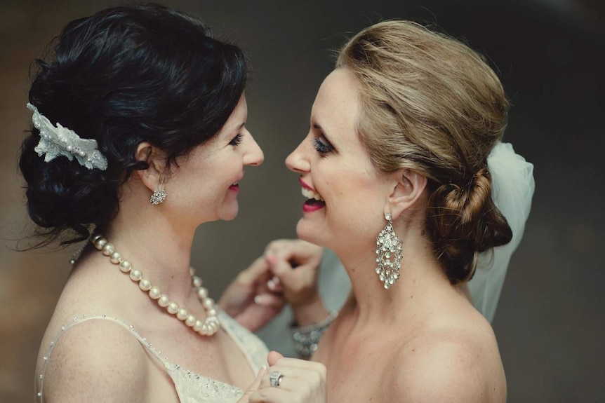 Leonie and Kate hold hand smiling towards each other on their wedding day in November 2011.