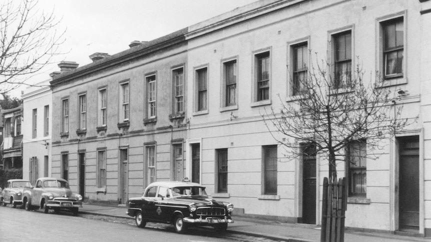 A black-and-white photograph of a row of two-storey Georgian townhouses.