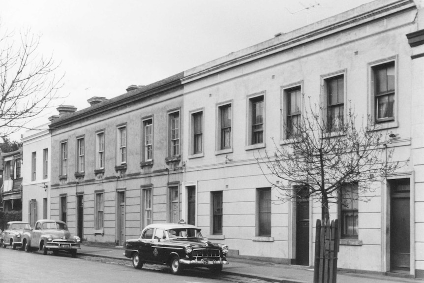 A black-and-white photograph of a row of two-storey Georgian townhouses.