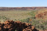 A rocky outcrop surrounded by a wide valley in Western Australia's Pilbara region.