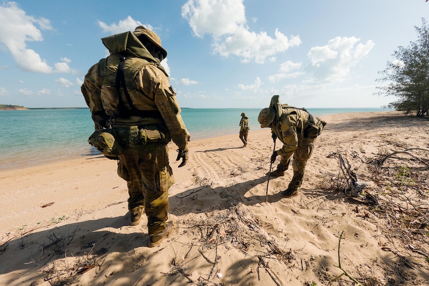 men in army uniform look for turtle eggs on tropical beach