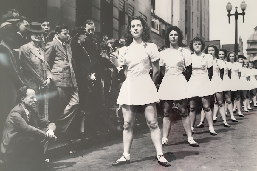 A black and white image of Physical culture women in dresses and ballet shoes in a public area in Sydney.