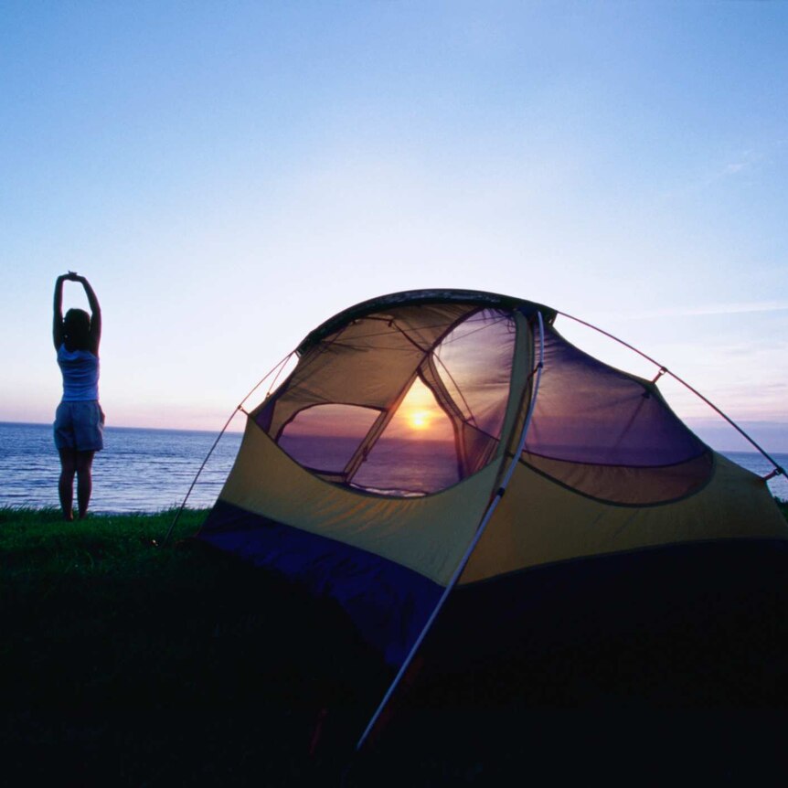 Person stretching outside tent at dawn