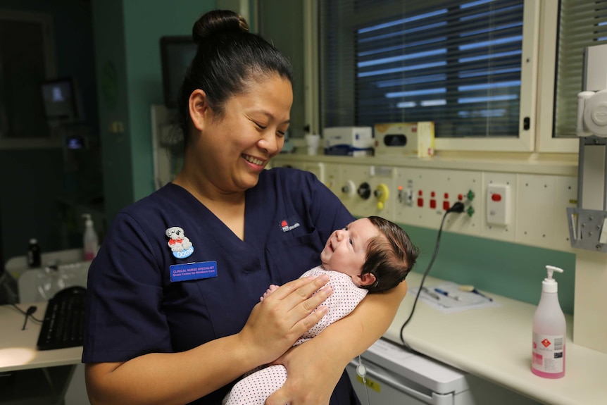 Donna De Mesa holds a baby in her arms showing someone who has a fulfilling job and good work satisfaction.