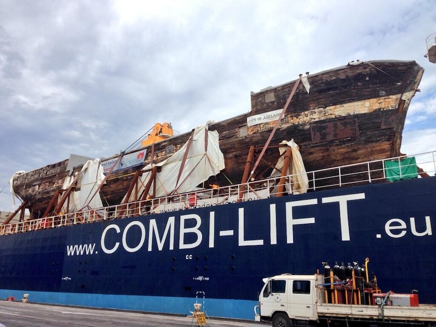 A heavy-lift cargo ship berthed at Port Adelaide with the restored hull of the City of Adelaide clipper on board.