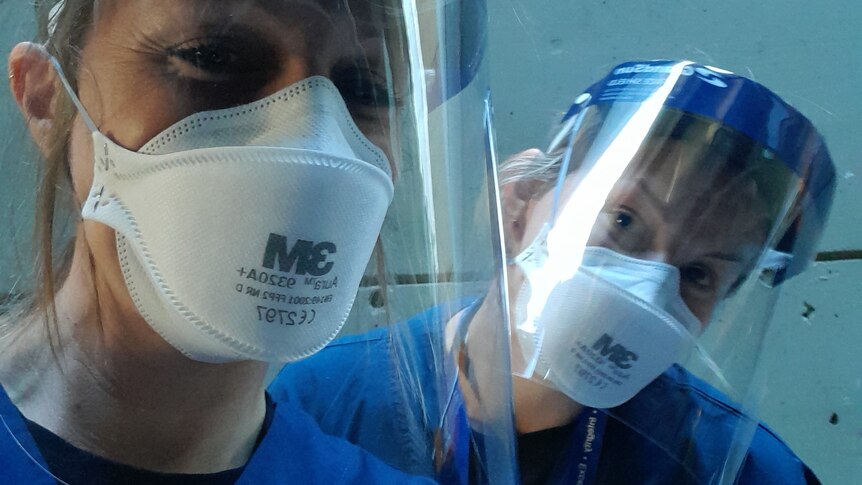 Two female nurses wearing personal protective equipment at a hospital.