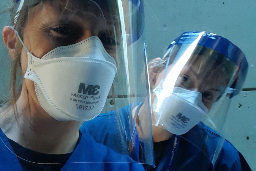Two female nurses wearing personal protective equipment at a hospital.