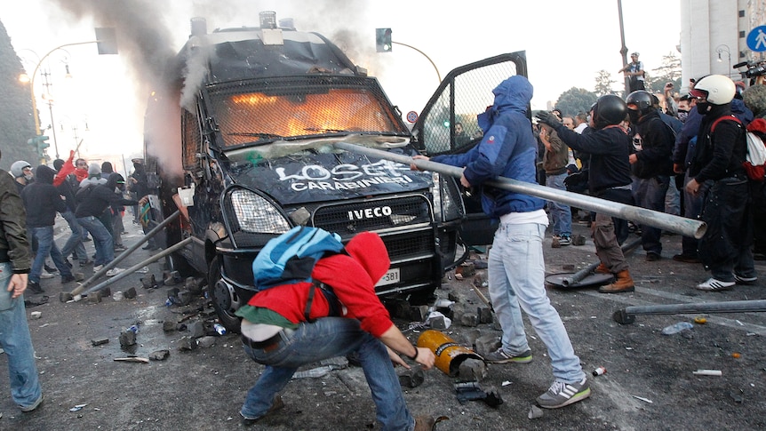 Demonstrators attack a police vehicle during a demonstration by the 'Indignant' group against banking and finance in Rome