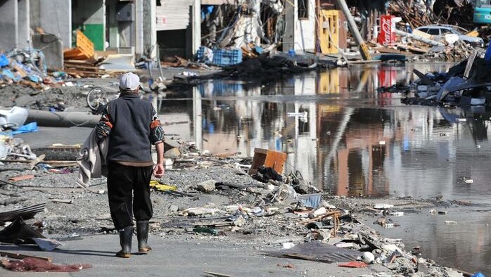 A man walks along a street through debris and past destroyed buildings in Kamaishi town, north-eastern Japan, on March 18, 2011.