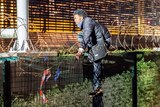 A migrant climbs a security fence of a Eurotunnel terminal near Calais