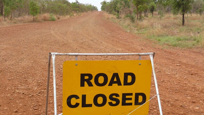 A road closed sign on a rocky dirt track