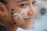 A girl has her face painted with a missing plane during a Day of Remembrance.