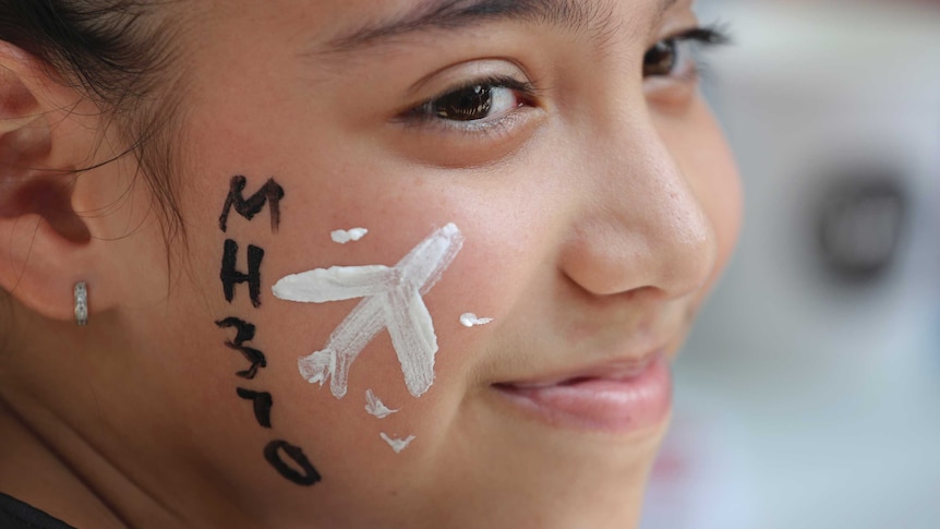 A girl has her face painted with a missing plane during a Day of Remembrance.