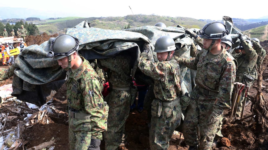 Soldiers carry the covered body of an earthquake victim.
