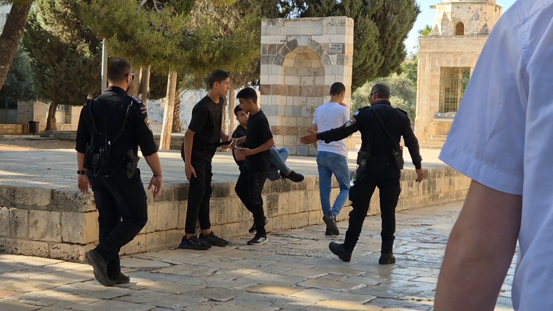 Two Israeli police officers move along a group of four teenagers who were hanging out 
