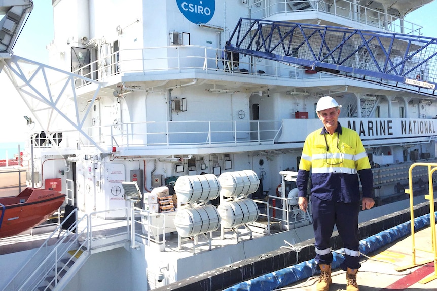 A man stands in front of a large ship