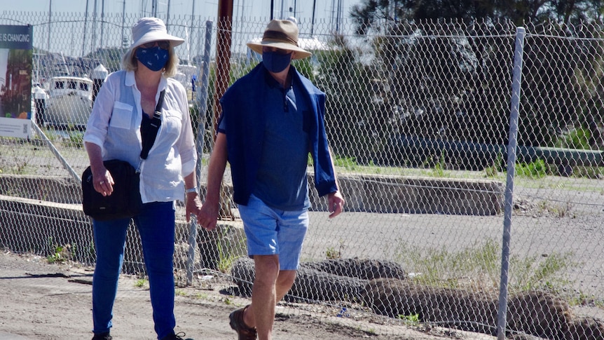 A middle aged couple holding hands on a morning walk.