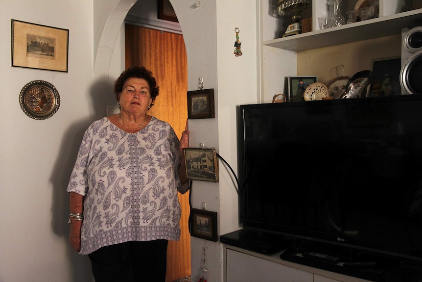 A photo of Darwin local Fiona Darcy leaning against an arch in her antique-filled living room in Darwin.