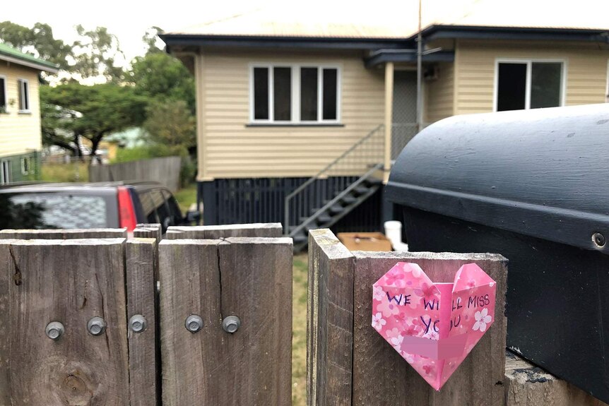 A heart-shaped note stuck on the front fence of a weatherboard house