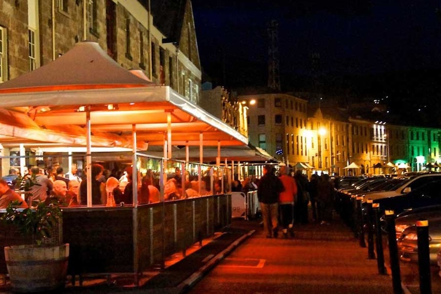 A street lit up at night, with restaurants and bars.