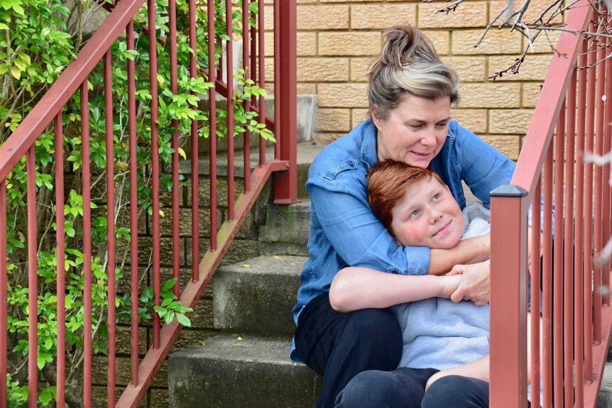 Cathy and Jacob James cuddle while sitting on some stairs to depict family life with a loved one with dementia.