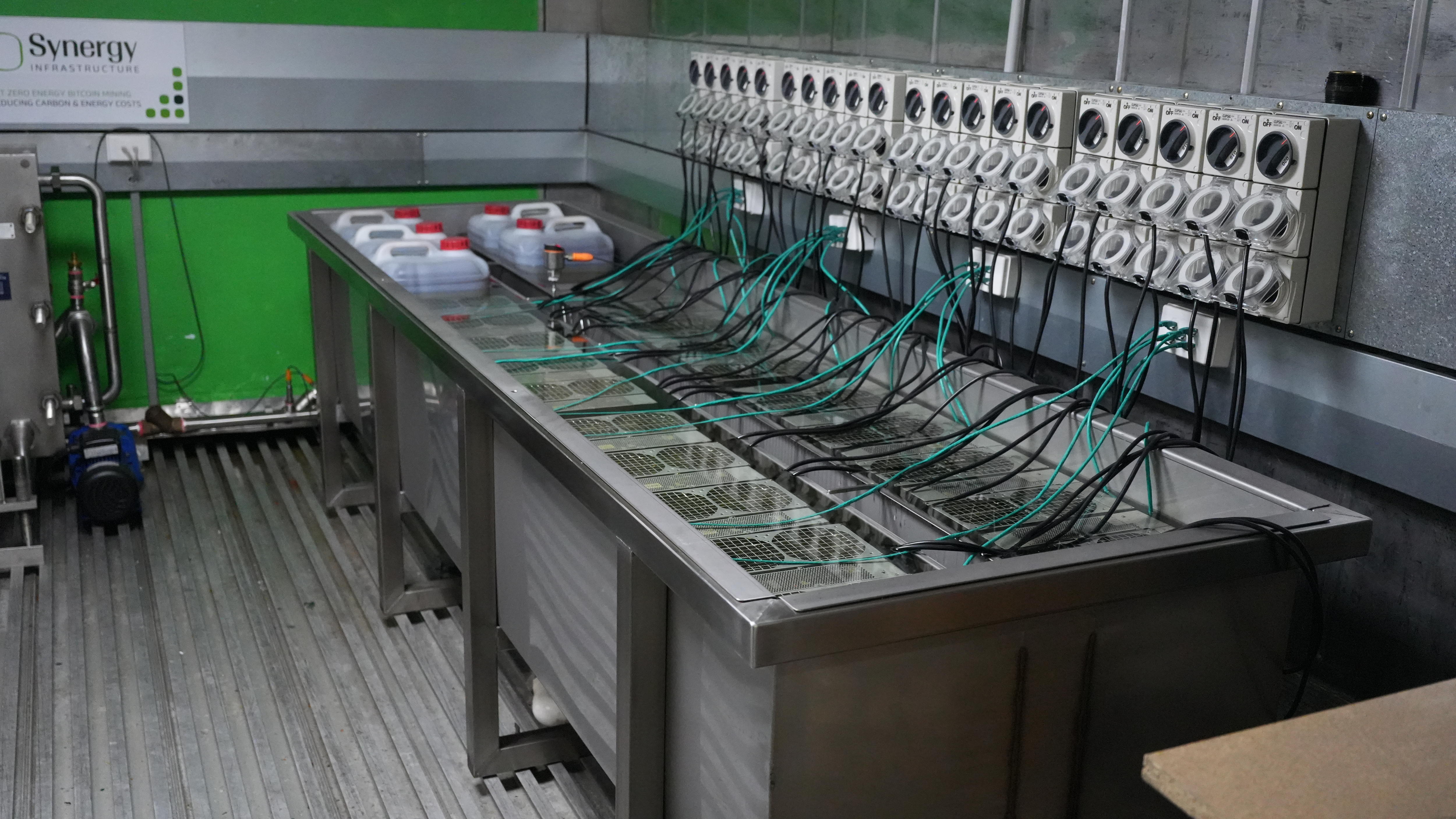 A large metal tub on a metal floor. It contains computer systems which are submerged in a non-conductive liquid.