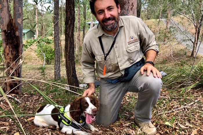 Dennis Gannaway kneels on ground with Danny the English Springer spaniel.