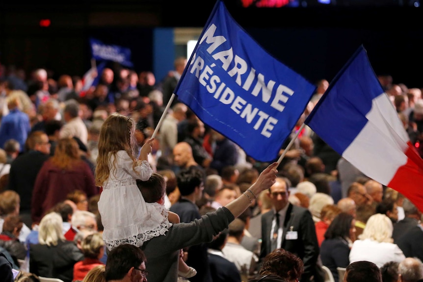 Supporters wave flags reading marine presidente as a little girl sits on her fathers shoulders