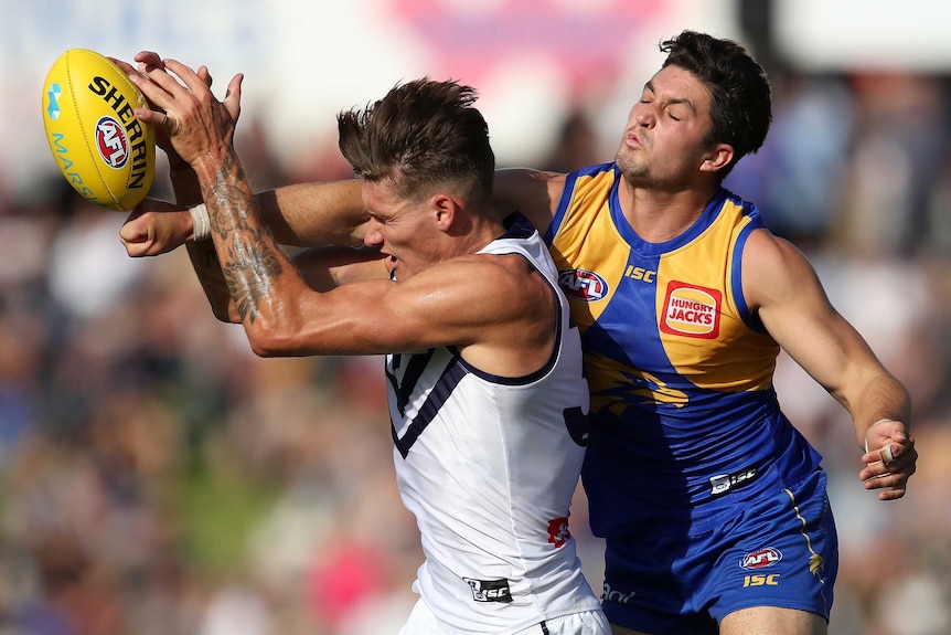 Rory Lobb comes under pressure from Tom Barrass as he tries to mark the football.