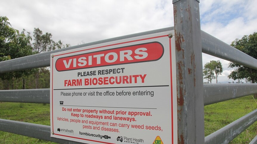 A close up of a white biosecurity sign with red and black writing.